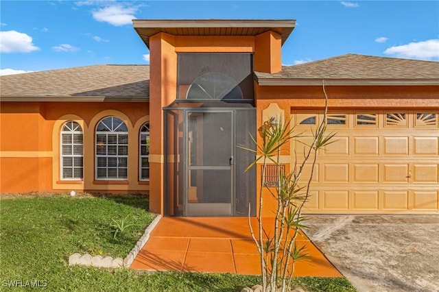 doorway to property with a shingled roof, an attached garage, and stucco siding