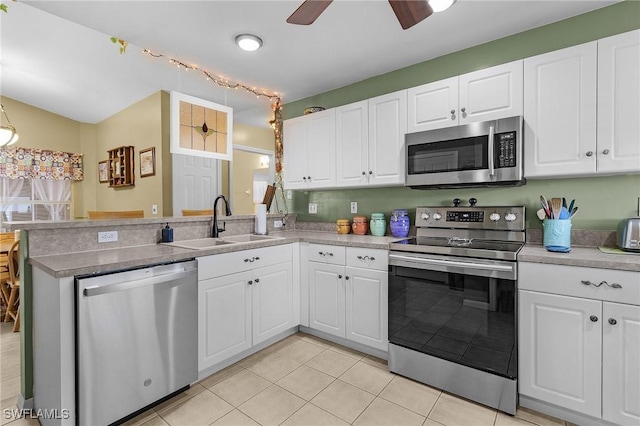 kitchen featuring stainless steel appliances, white cabinetry, a sink, and a peninsula