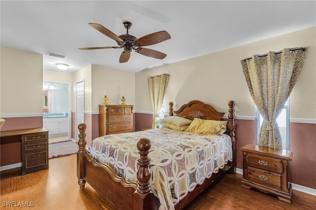 bedroom featuring ensuite bathroom, ceiling fan, wood finished floors, visible vents, and baseboards