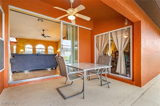 carpeted dining room featuring ceiling fan, a textured wall, and visible vents