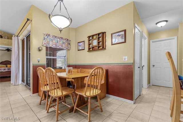 dining space with light tile patterned floors and a wainscoted wall