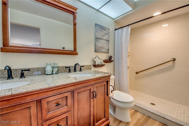 full bath with double vanity, wood finished floors, a sink, and a shower stall