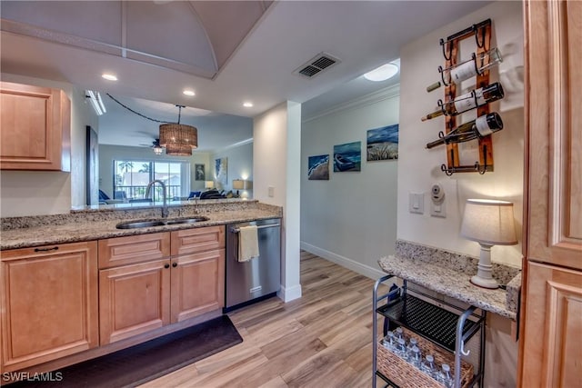 kitchen featuring visible vents, stainless steel dishwasher, crown molding, light wood-style floors, and a sink