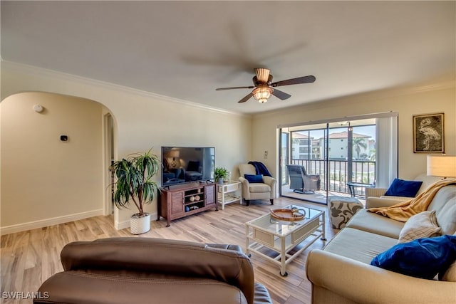 living room featuring baseboards, light wood-type flooring, a ceiling fan, and crown molding