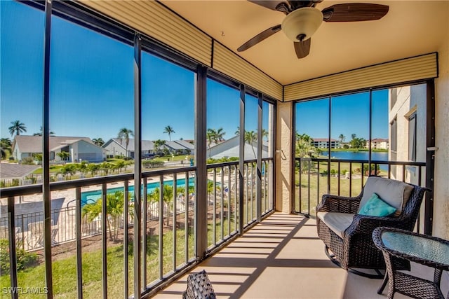 sunroom featuring a water view and a ceiling fan