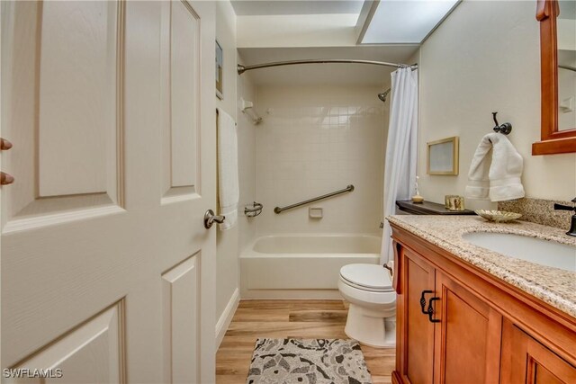 full bath featuring toilet, shower / bath combination with curtain, wood finished floors, and vanity