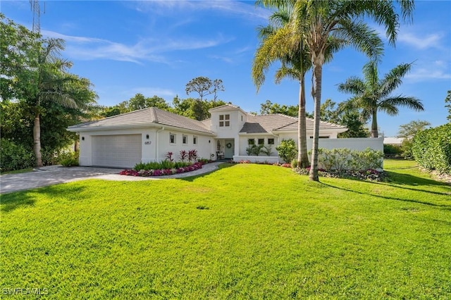 mediterranean / spanish home featuring a garage, a front yard, driveway, and stucco siding