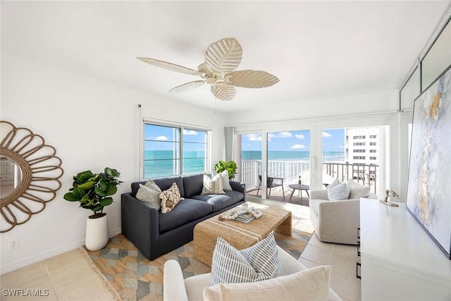 living area with light tile patterned flooring, ceiling fan, baseboards, and a water view