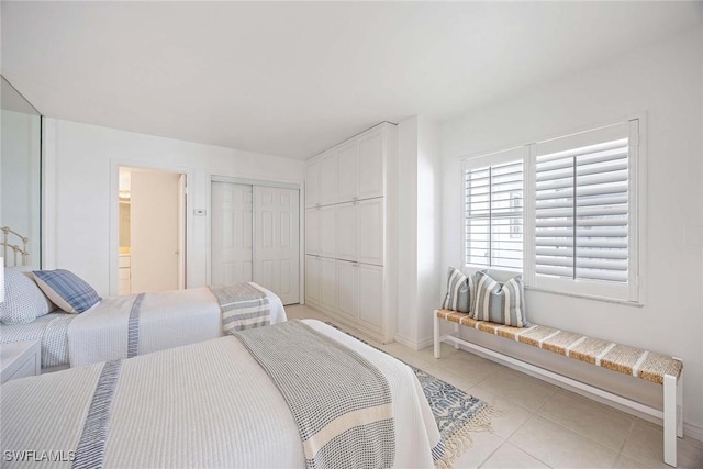 bedroom featuring light tile patterned floors, connected bathroom, baseboards, and a closet