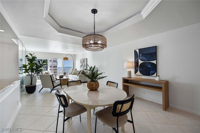 dining space with light tile patterned floors, a raised ceiling, and crown molding