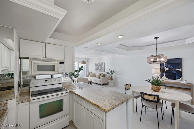 kitchen with light stone counters, a tray ceiling, white appliances, and white cabinetry