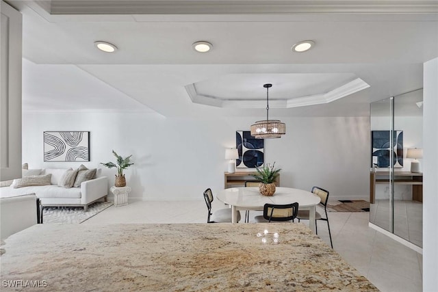 dining area featuring ornamental molding, a tray ceiling, baseboards, and light tile patterned floors