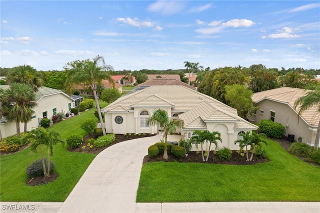 mediterranean / spanish house with concrete driveway, a tile roof, a front lawn, and stucco siding