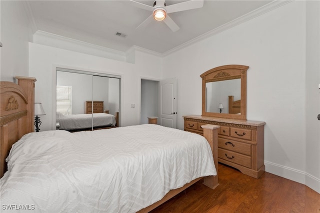 bedroom with baseboards, visible vents, ornamental molding, wood finished floors, and a closet