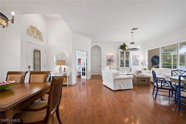 dining room featuring visible vents, arched walkways, ornamental molding, wood finished floors, and a chandelier