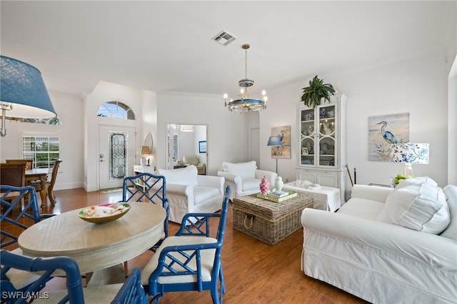 interior space with visible vents, a chandelier, wood finished floors, and ornamental molding