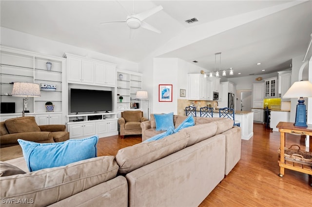 living room with lofted ceiling, a ceiling fan, visible vents, and light wood-style floors