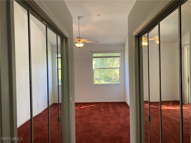 hallway with baseboards and dark colored carpet