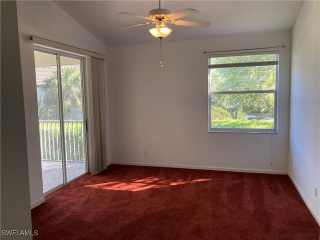 spare room with dark colored carpet, a healthy amount of sunlight, lofted ceiling, and baseboards