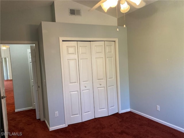 unfurnished bedroom with lofted ceiling, a closet, visible vents, and dark carpet