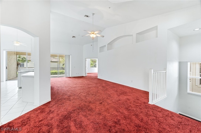 spare room with light carpet, arched walkways, a healthy amount of sunlight, and ceiling fan