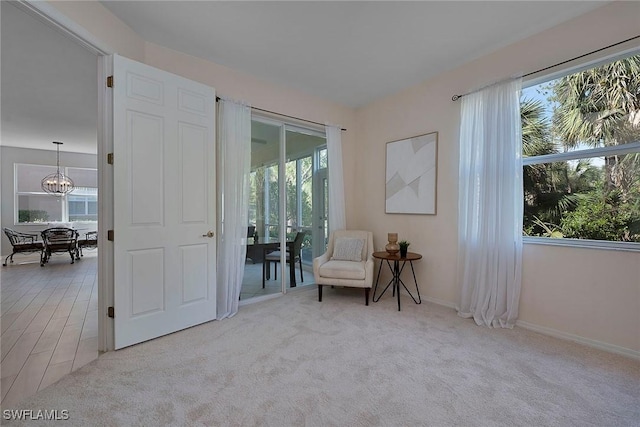 sitting room featuring light carpet, a notable chandelier, and baseboards