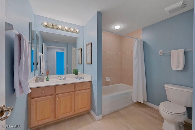 bathroom with visible vents, toilet, shower / tub combo, vanity, and baseboards