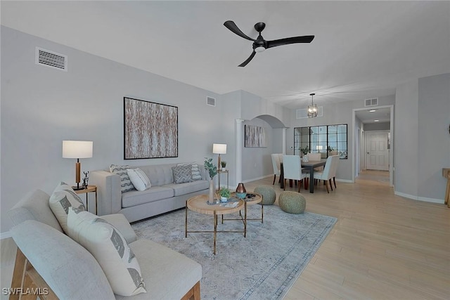 living room featuring light wood-style floors, visible vents, and arched walkways