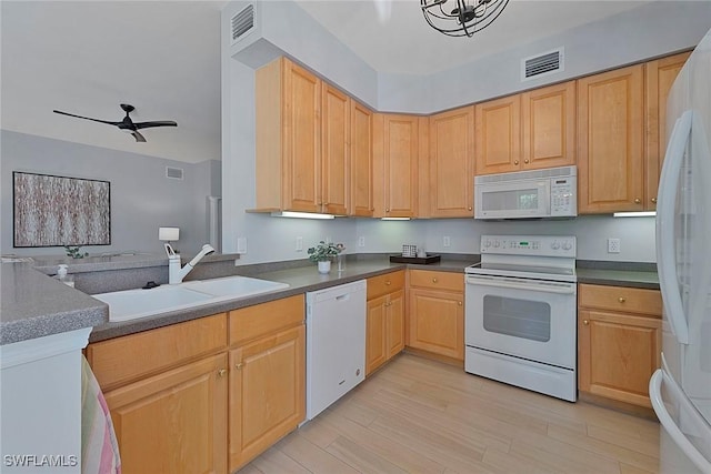 kitchen with dark countertops, light brown cabinetry, a sink, light wood-type flooring, and white appliances