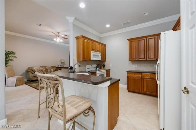 kitchen with dark countertops, open floor plan, a sink, white appliances, and a peninsula