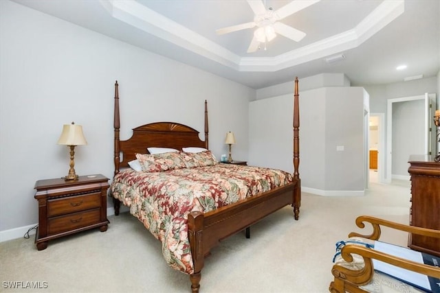 bedroom with a ceiling fan, a tray ceiling, light colored carpet, and baseboards