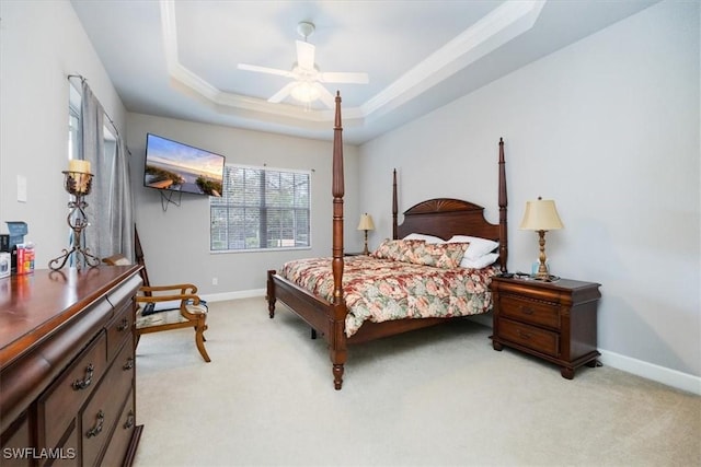 bedroom featuring light carpet, baseboards, a raised ceiling, and a ceiling fan