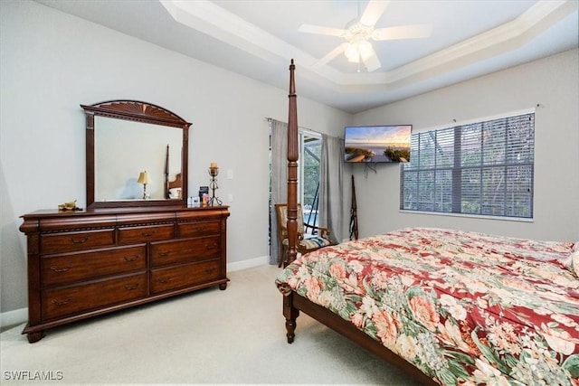 bedroom featuring light colored carpet, a ceiling fan, baseboards, access to exterior, and a tray ceiling