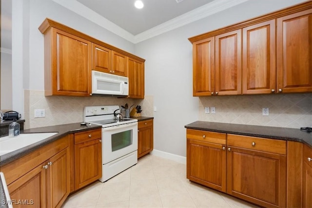 kitchen with light tile patterned flooring, white appliances, a sink, brown cabinetry, and dark countertops