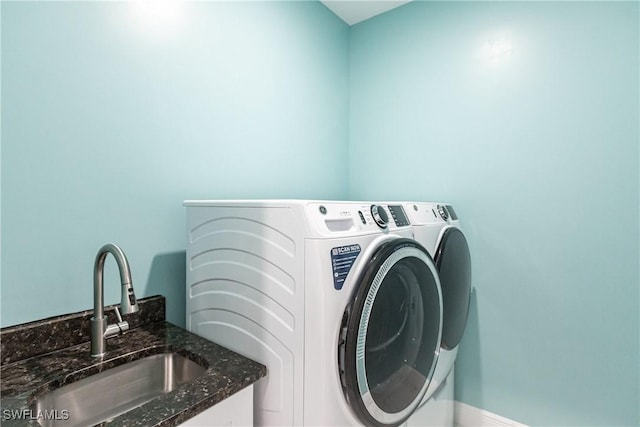 washroom with laundry area, washing machine and clothes dryer, and a sink