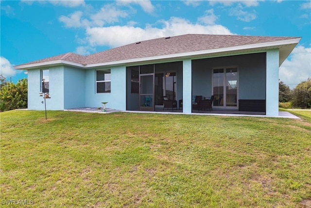 rear view of property featuring a sunroom, roof with shingles, a lawn, and stucco siding