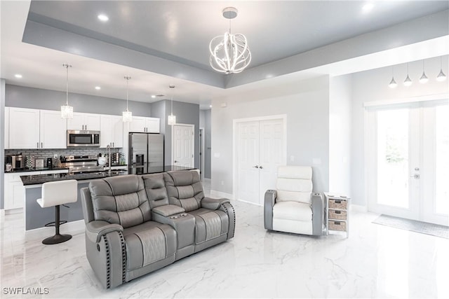 living area featuring baseboards, marble finish floor, a tray ceiling, and recessed lighting