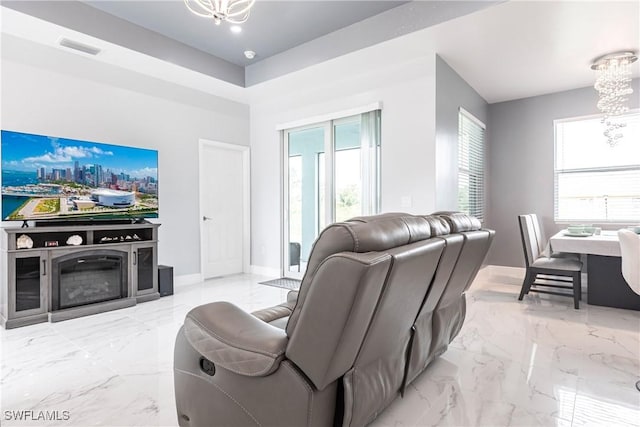 living area with marble finish floor, a wealth of natural light, visible vents, and a notable chandelier