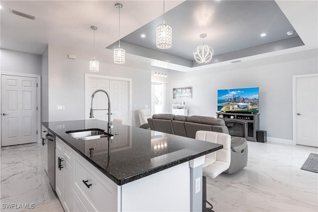 kitchen with marble finish floor, a center island with sink, visible vents, a sink, and dark stone countertops