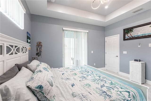 bedroom with visible vents, a tray ceiling, and baseboards