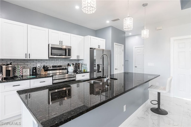 kitchen with marble finish floor, tasteful backsplash, appliances with stainless steel finishes, white cabinetry, and a sink