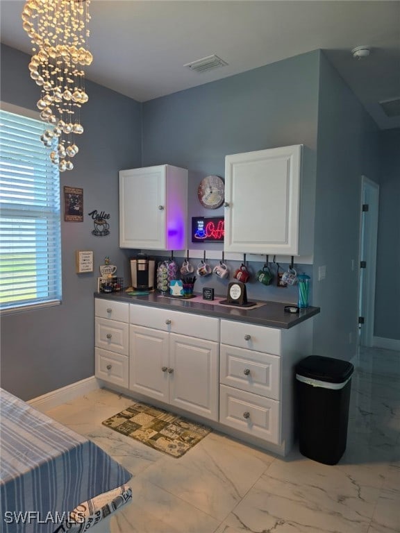 kitchen with marble finish floor, dark countertops, and visible vents