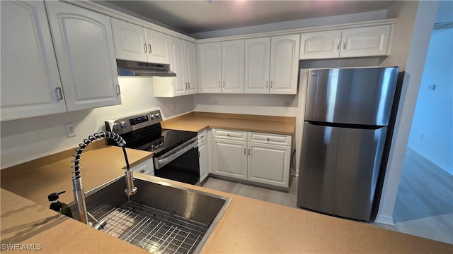 kitchen with under cabinet range hood, appliances with stainless steel finishes, white cabinets, and a sink