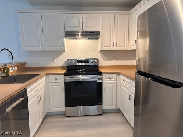 kitchen with light wood-style flooring, under cabinet range hood, stainless steel appliances, a sink, and white cabinetry