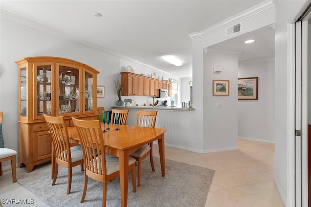 dining area featuring light tile patterned floors, baseboards, visible vents, and crown molding