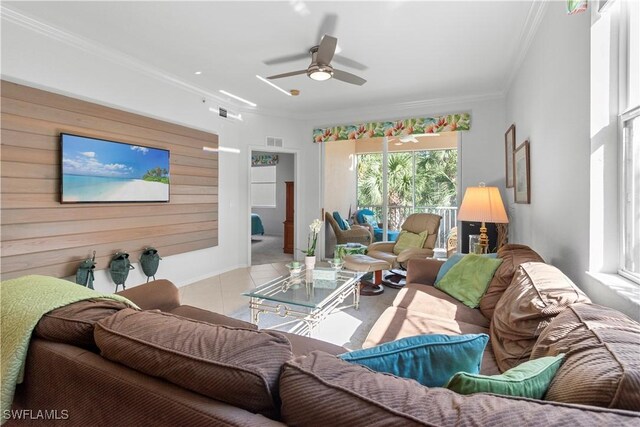 tiled living room featuring a ceiling fan, visible vents, crown molding, and wooden walls