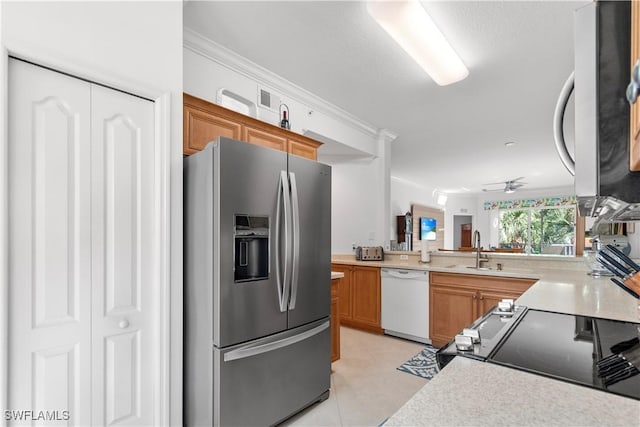 kitchen featuring light countertops, appliances with stainless steel finishes, a sink, and brown cabinets