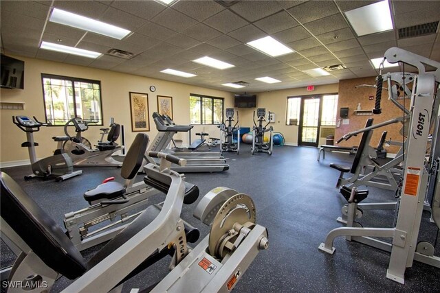 exercise room with a drop ceiling, visible vents, and baseboards