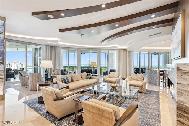 living room featuring a wealth of natural light, marble finish floor, a tray ceiling, and recessed lighting