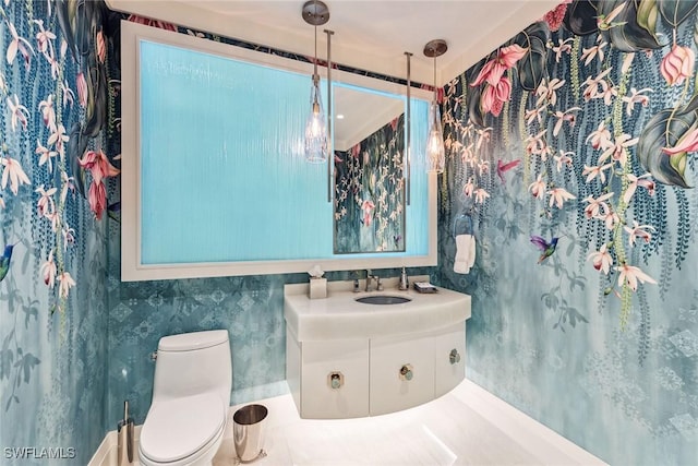 bathroom with vanity, toilet, and wallpapered walls